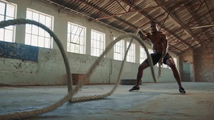 健身男子在废弃仓库里做战斗绳锻炼