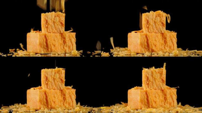 磨碎的奶酪切达干酪小块落在大块上。