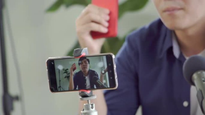 年轻的亚洲男性正在他们的智能手机上进行直播，以推荐该行业的产品。