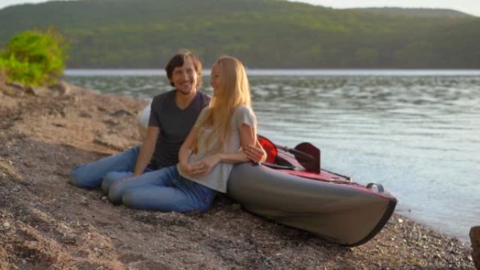 年轻的男人和女人坐在他们的充气皮划艇在湖或海边。慢动作镜头