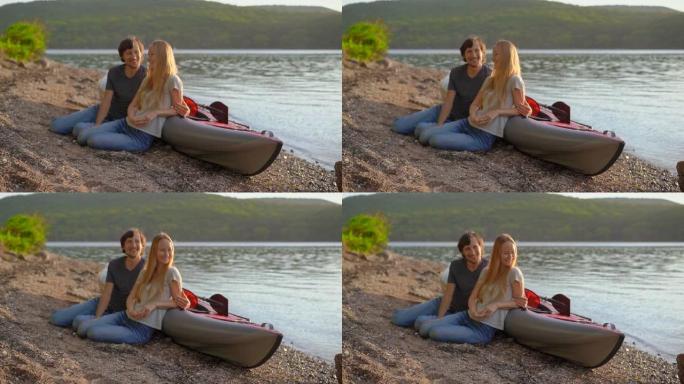 年轻的男人和女人坐在他们的充气皮划艇在湖或海边。慢动作镜头