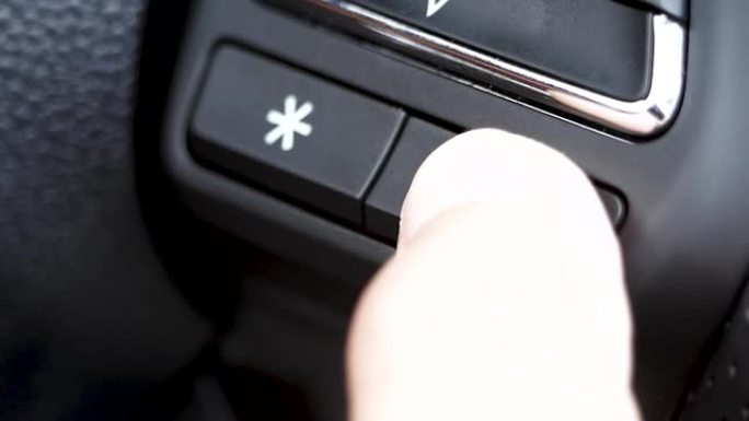 开车时手指按下方向盘上的智能系统按钮语音控制 (i-smart) 的特写。