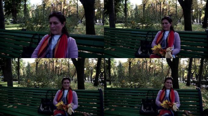 年轻女子坐在秋天公园的长凳上。Steadicam射击