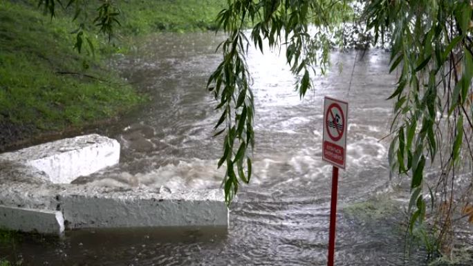 在大雨中，下水道的一股脏水排入河中。前面是一个标志 -- 禁止游泳。环境污染。概念。4K