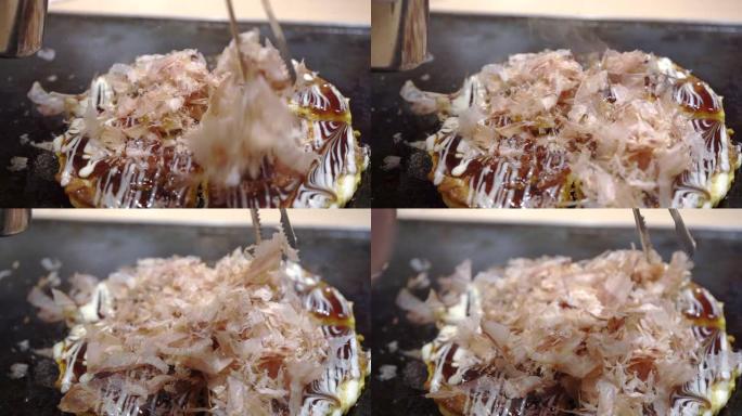慢动作视频介绍okonomiyaki一边烹饪，一边撒上世界著名的当地美食干鱼日本披萨。