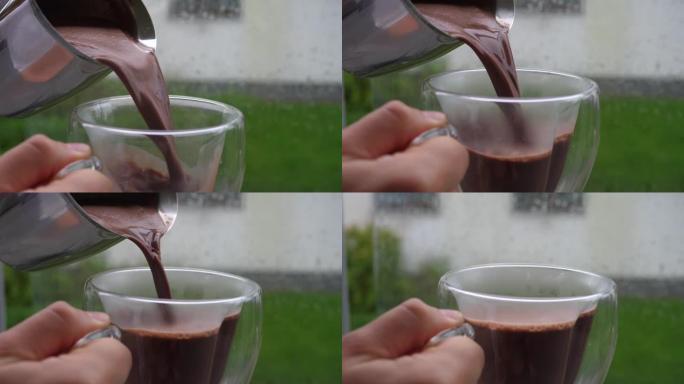 在下雨天，将钢水罐中的热巧克力倒入玻璃杯中