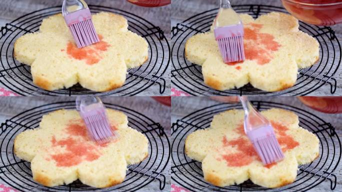 用糖浆浸泡海绵蛋糕层。糕点师正在制作花朵形状的粉红色蛋糕。