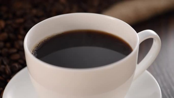 在烘焙咖啡豆背景下的杯子里的咖啡