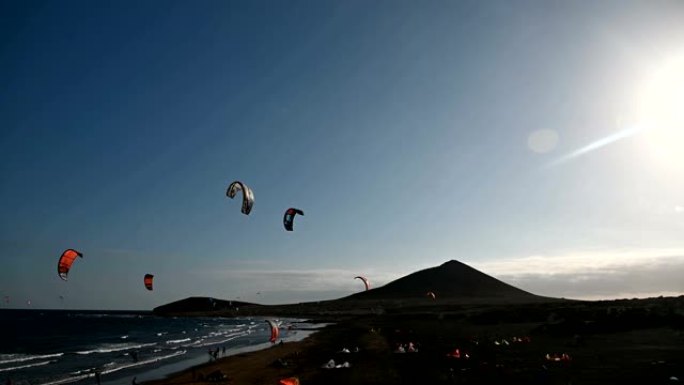 在大风天，海滩上有许多五颜六色的风筝和风筝冲浪者乘风破浪