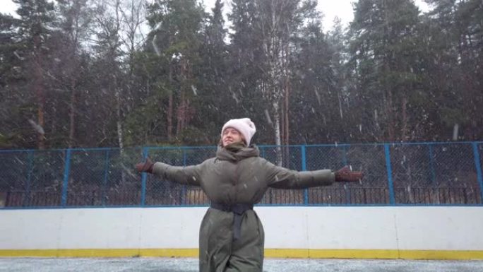 快乐的年轻女子在第一场雪时欢欣鼓舞，在运动场上奔跑和旋转，溜冰场。新年。圣诞节。冬天的心情。大雪花。