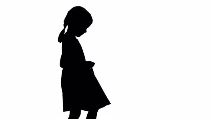 穿着黑色连衣裙的轮廓美丽小女孩带着购物袋散步