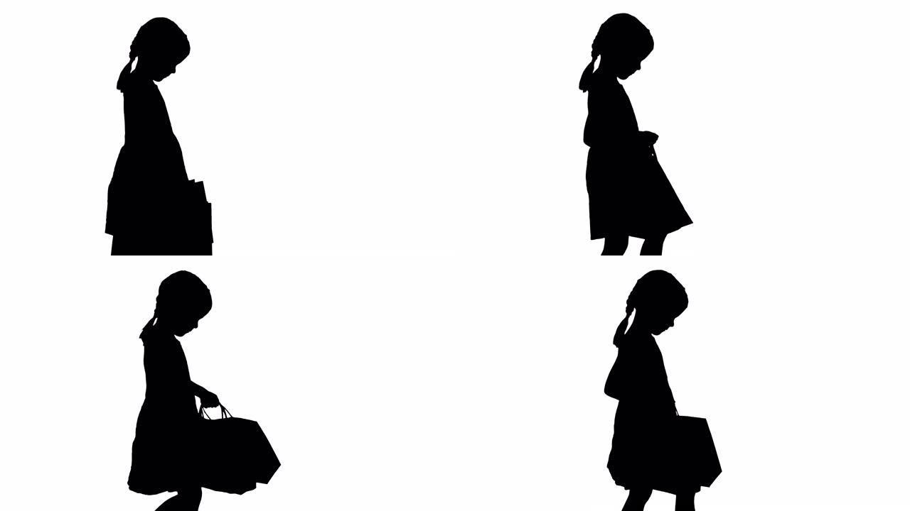 穿着黑色连衣裙的轮廓美丽小女孩带着购物袋散步
