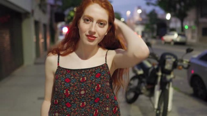 可爱的长着雀斑的红发女人在夜晚的城市街道上
