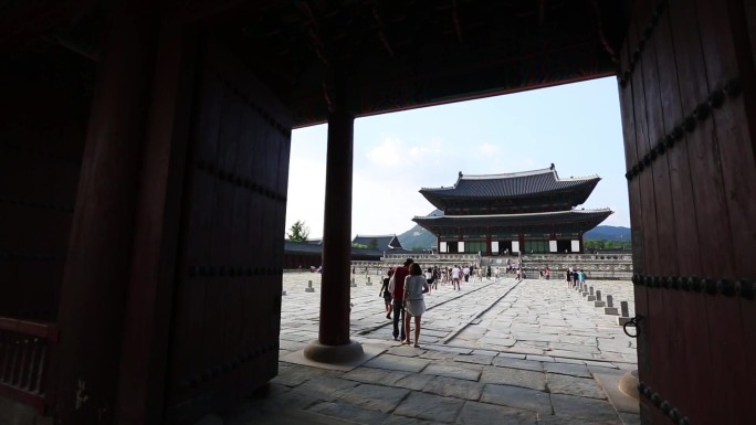 神社前有一盏红灯笼 一张桌子上放着很多食物 人们走在建筑物前的街道上