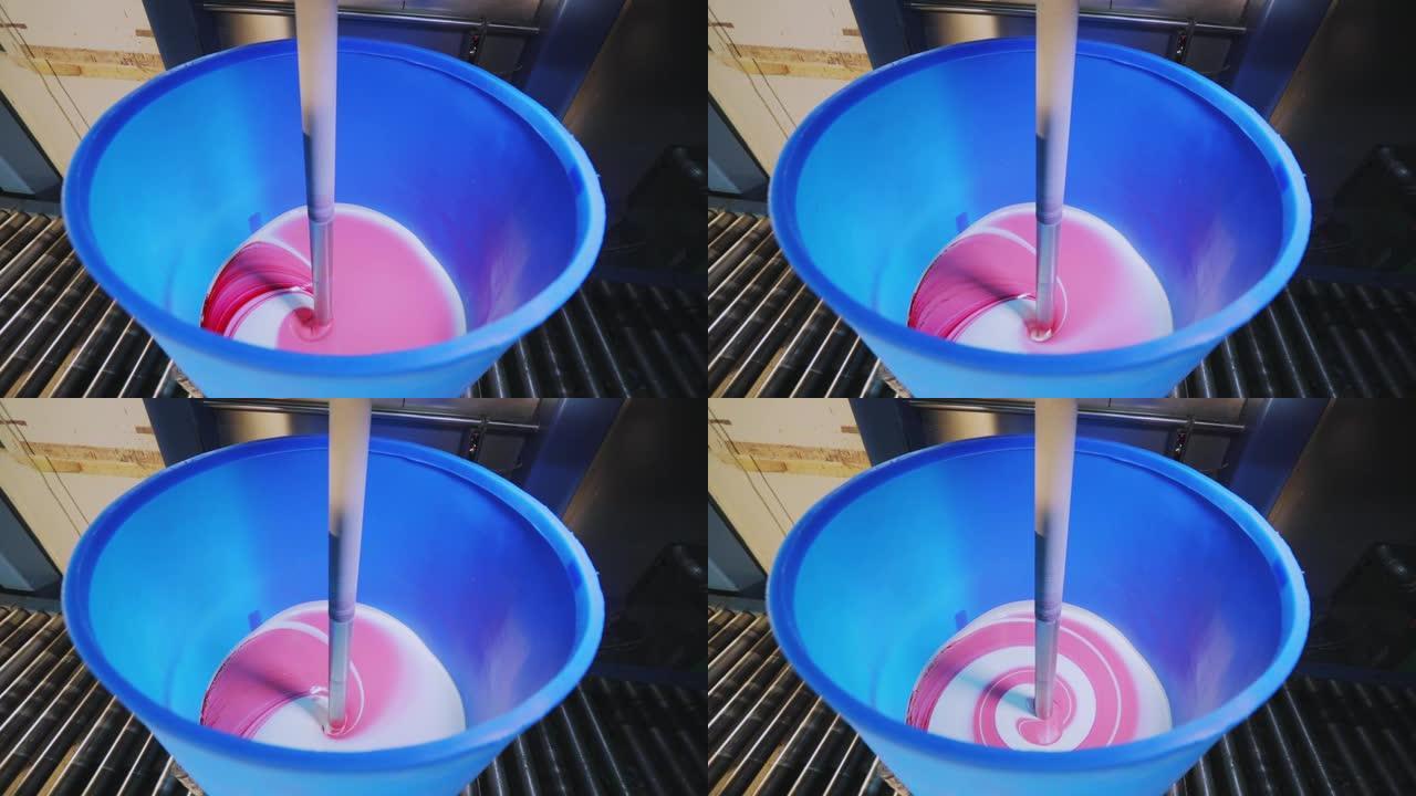 在工厂里混合粉色油漆。在桶中混合油漆，在工厂中混合油漆