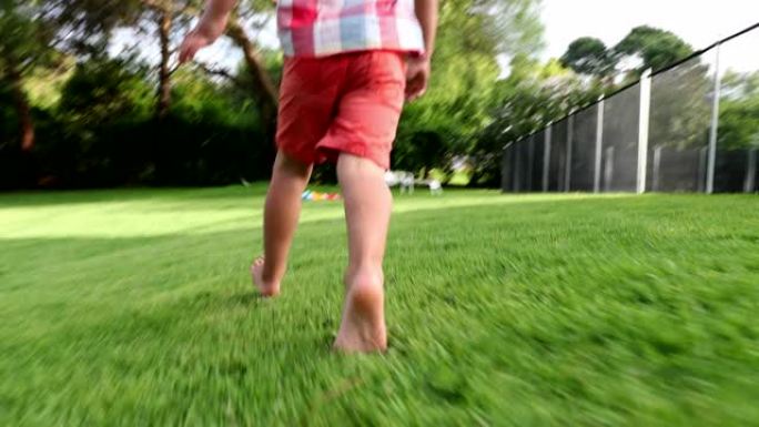 婴儿蹒跚学步的男孩在后院花园户外跑步