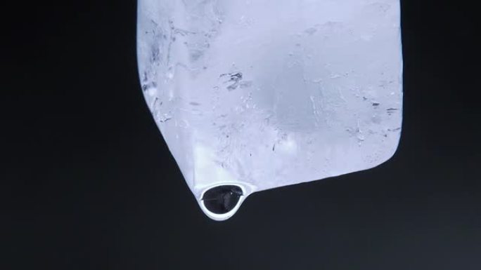 黑色背景下融化冰块的微距视频拍摄。落下水滴的冰块。特写镜头