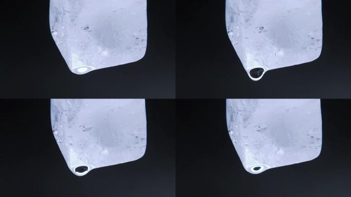 黑色背景下融化冰块的微距视频拍摄。落下水滴的冰块。特写镜头