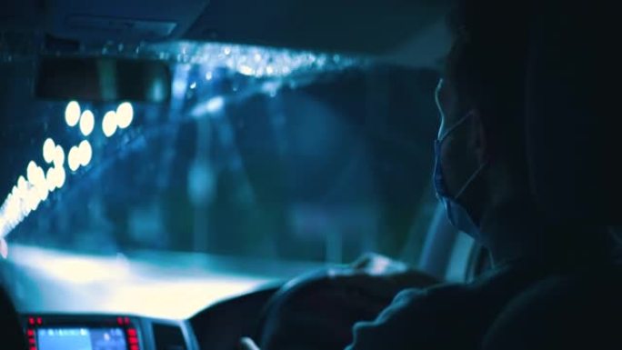 戴医用口罩的年轻人驾驶汽车通过夜间多雨的高速公路