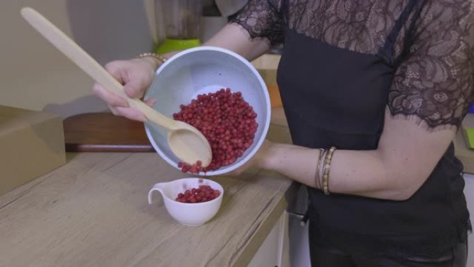 女人在小白碗中装小红莓