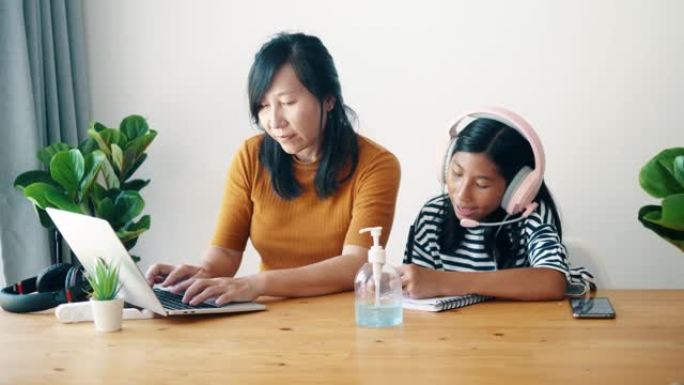 亚洲母亲和她的女儿在新型冠状病毒肺炎期间在家工作。