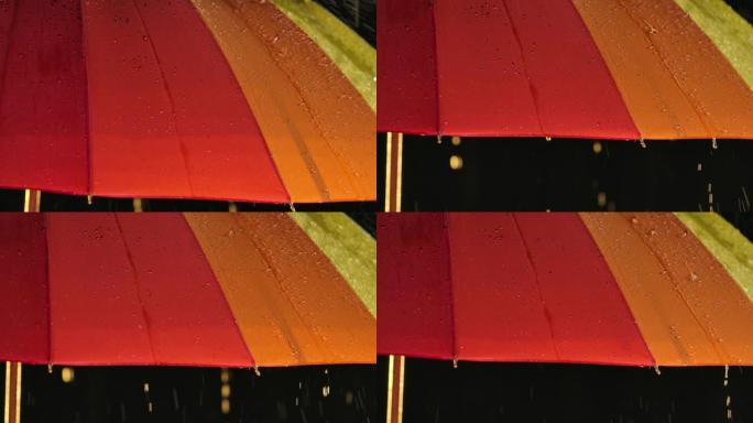 雨中明亮的彩虹伞在封闭的黑暗工作室里。以慢动作拍摄特写