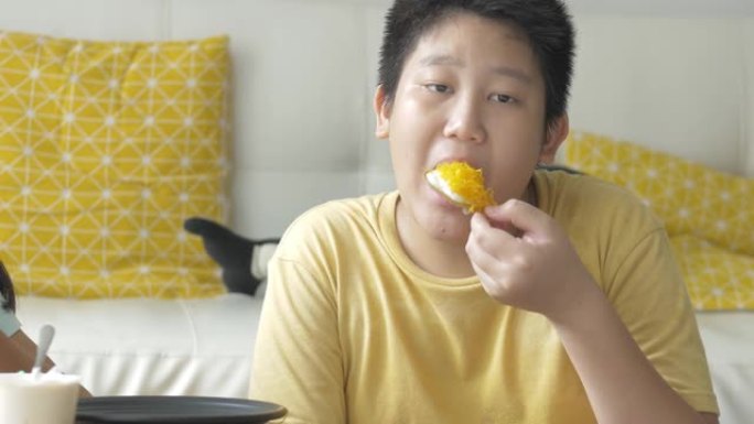 快乐的亚洲男孩在家吃黄油奶油零食，生活方式理念。