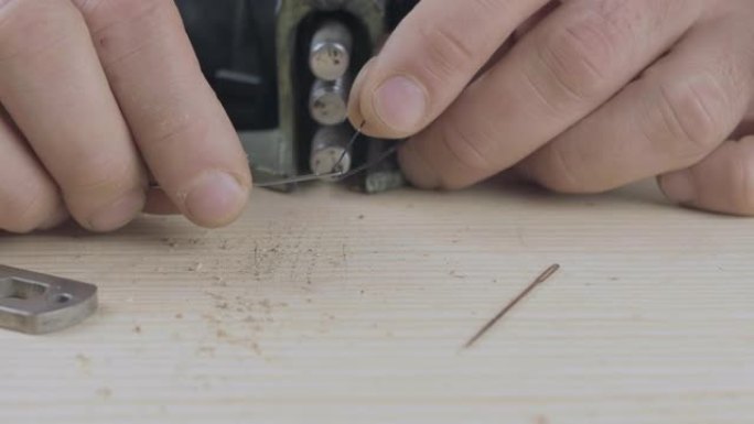 男性双手的特写镜头将黑线插入针中，用于在皮革上缝制。手工制品。电影院4k视频。C4k