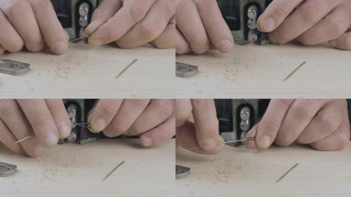 男性双手的特写镜头将黑线插入针中，用于在皮革上缝制。手工制品。电影院4k视频。C4k