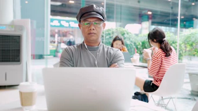 时髦的男人在咖啡店里使用公共互联网连接在电脑上观看在线电影。