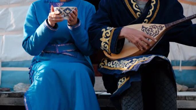 穿着亚洲衣服的夫妇坐在蒙古包的台阶上