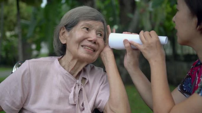 女儿用纸管与听力受损的老年妇女交谈