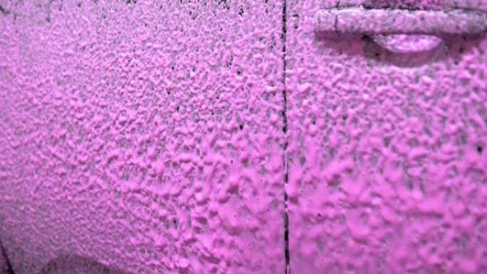 在车身上喷涂粉红色泡沫。特写