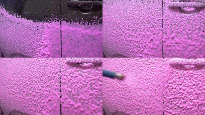 在车身上喷涂粉红色泡沫。特写