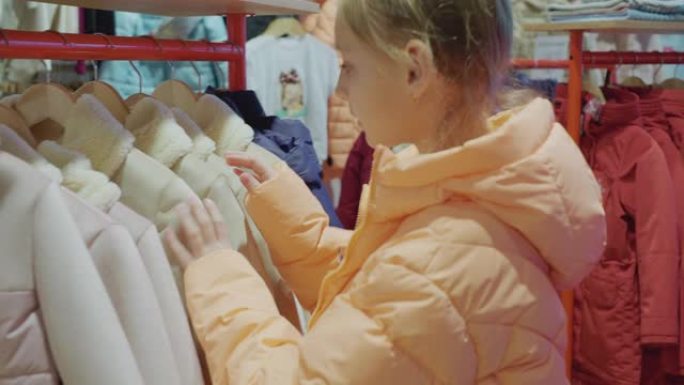 十几岁的女孩在时尚陈列室选择夹克。年轻女子在商店里看衣服。少女在服装店购物。