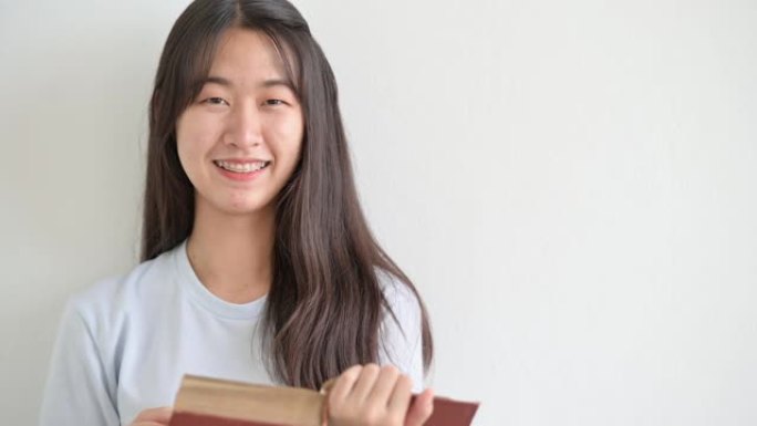 一名亚洲女大学生对着大学微笑，盯着镜头。
