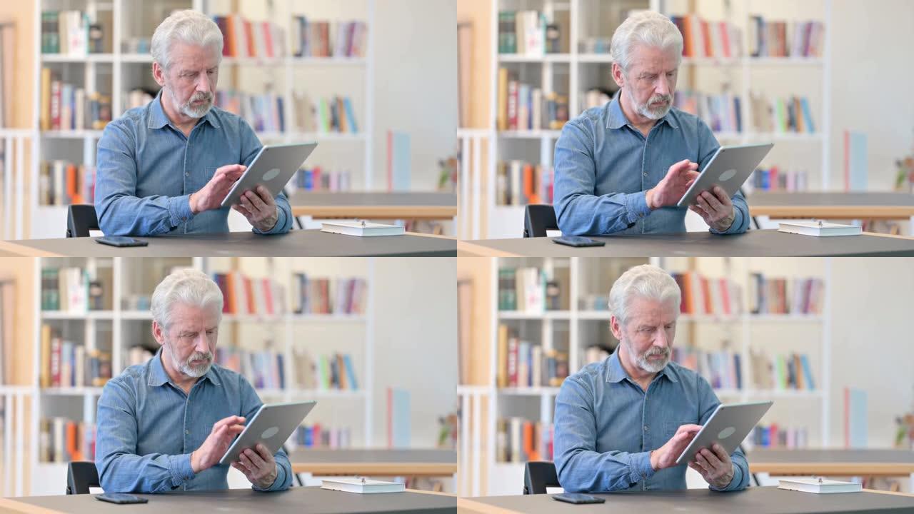 开朗的高级老人在图书馆使用平板电脑