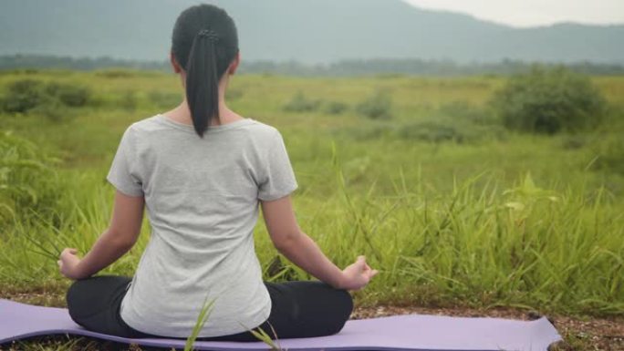 迷人的年轻亚洲女性做瑜伽练习冥想，在日出时在美丽的山景中表演精神瑜伽姿势。
