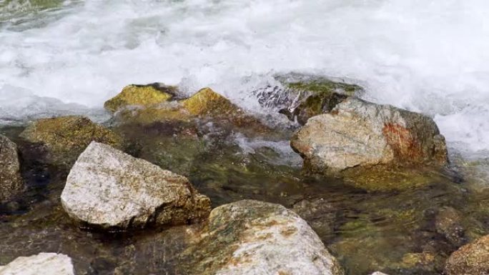 春天的快速河流流过岩石，在晴天形成白色波浪