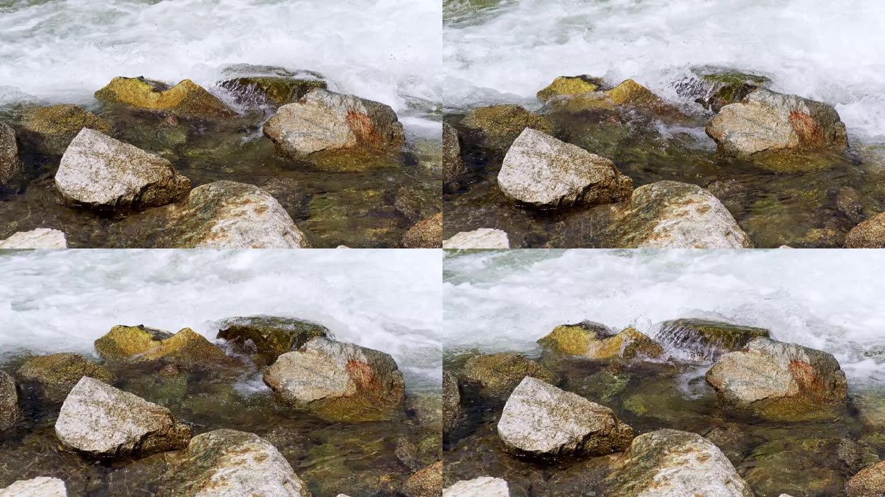春天的快速河流流过岩石，在晴天形成白色波浪