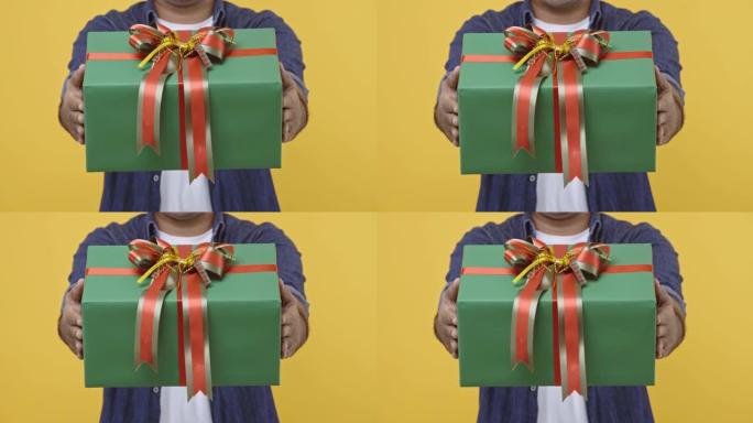 圣诞快乐，新2021年男手握着礼物盒。给盒子的人在孤立的黄色背景上庆祝他的生日。4k分辨率。