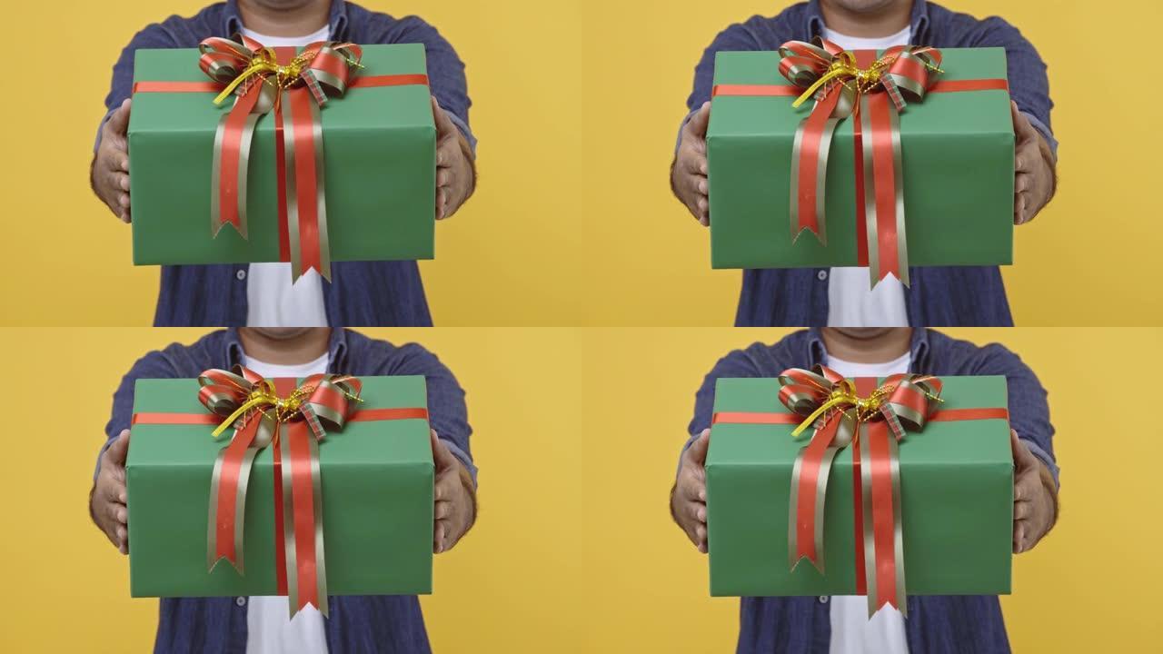 圣诞快乐，新2021年男手握着礼物盒。给盒子的人在孤立的黄色背景上庆祝他的生日。4k分辨率。