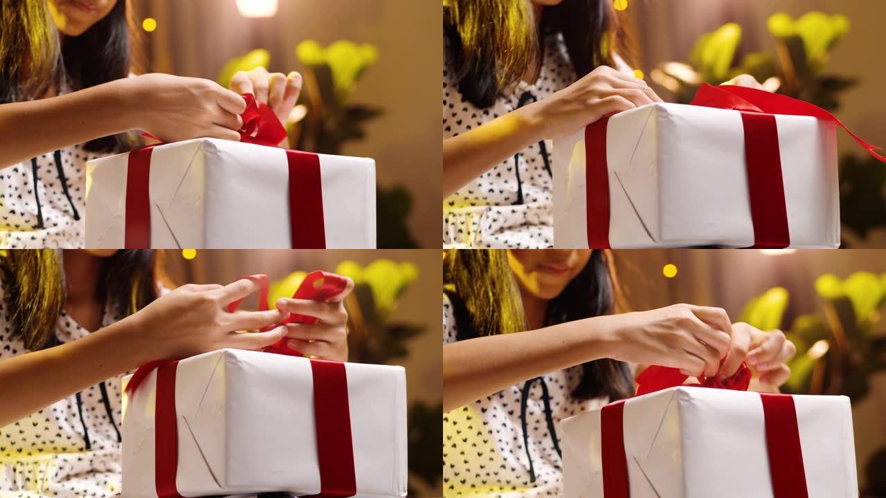 圣诞节用红丝带包装亚洲女孩礼品盒。