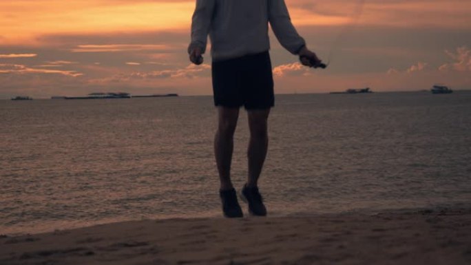 穿着运动服的亚洲年轻人的剪影使用速度绳在海滩上进行户外运动美丽的日落。