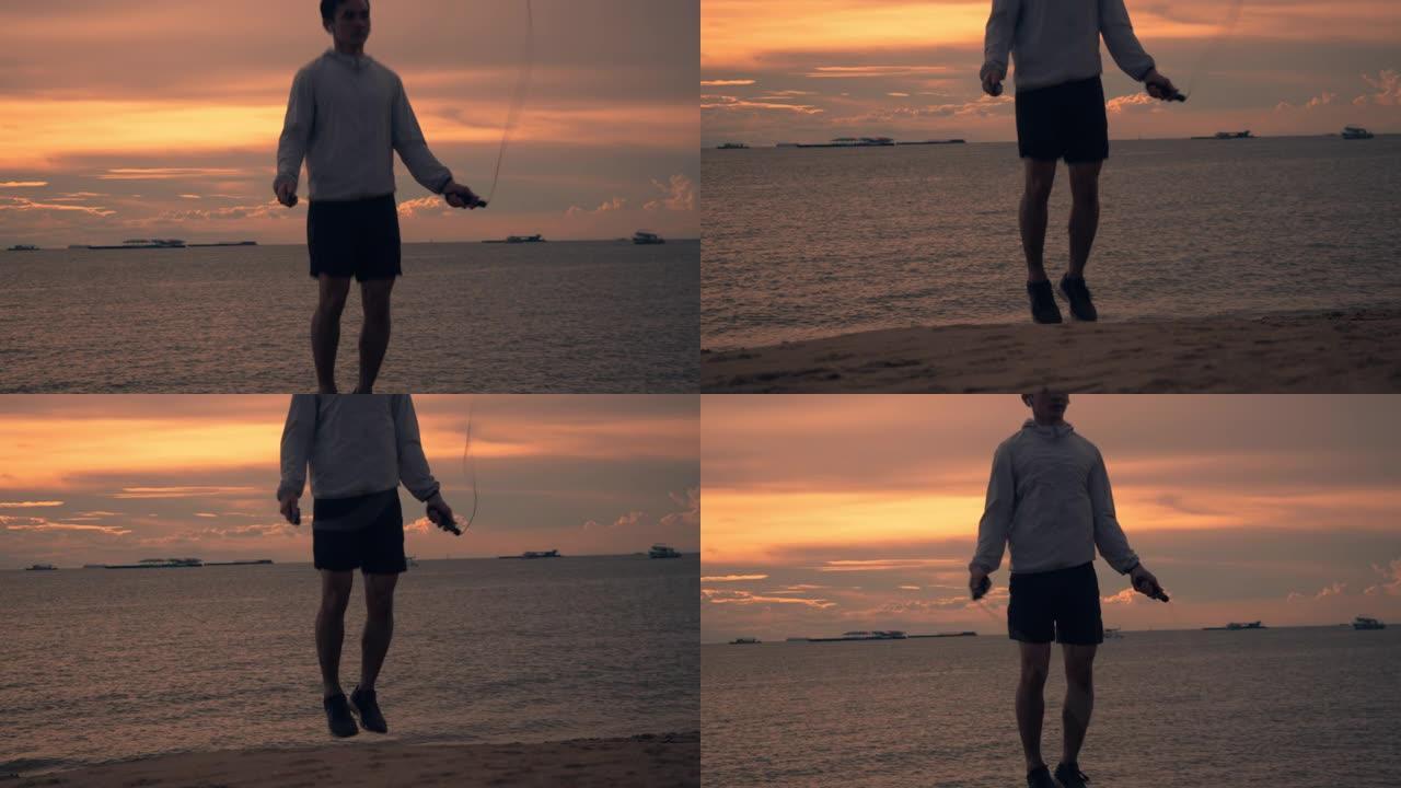 穿着运动服的亚洲年轻人的剪影使用速度绳在海滩上进行户外运动美丽的日落。