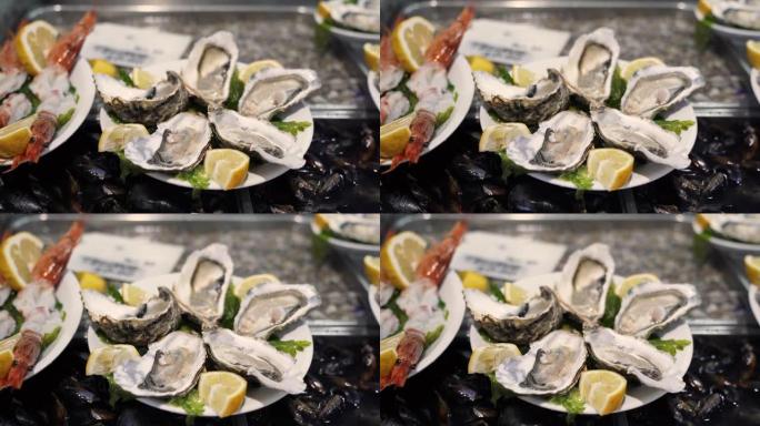 半壳上的新鲜地中海牡蛎，柠檬片放在冰中的白色盘子上。欧洲传统鱼市场的海洋美食。昂贵的海鲜，美味健康的