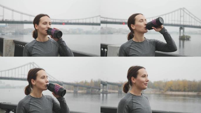年轻漂亮的运动女运动员穿着保暖内衣，跑步训练后喝等渗。女跑步者在户外锻炼后从瓶子里喝水
