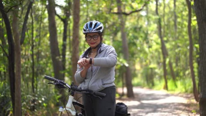 公园里的高级亚洲女性自行车，用智能手表检查时间或心率