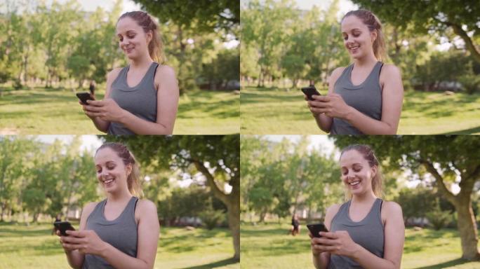 白种人适合年轻女子在阳光明媚的早晨在公园用手机发短信时微笑