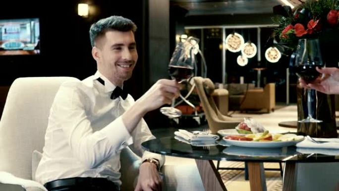 微笑的男人和女人在餐馆里用红酒碰杯。4K